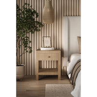 Bedside table with plant next to white upholstered bed.
