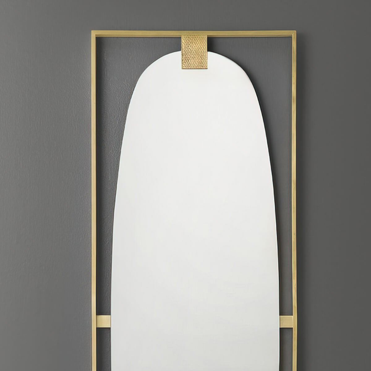 Brass wall mirror on gray wall, close-up.