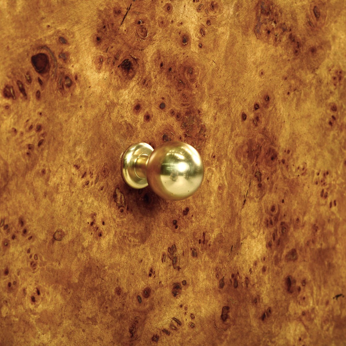 Gold knob on Art Deco burl wood nightstand.