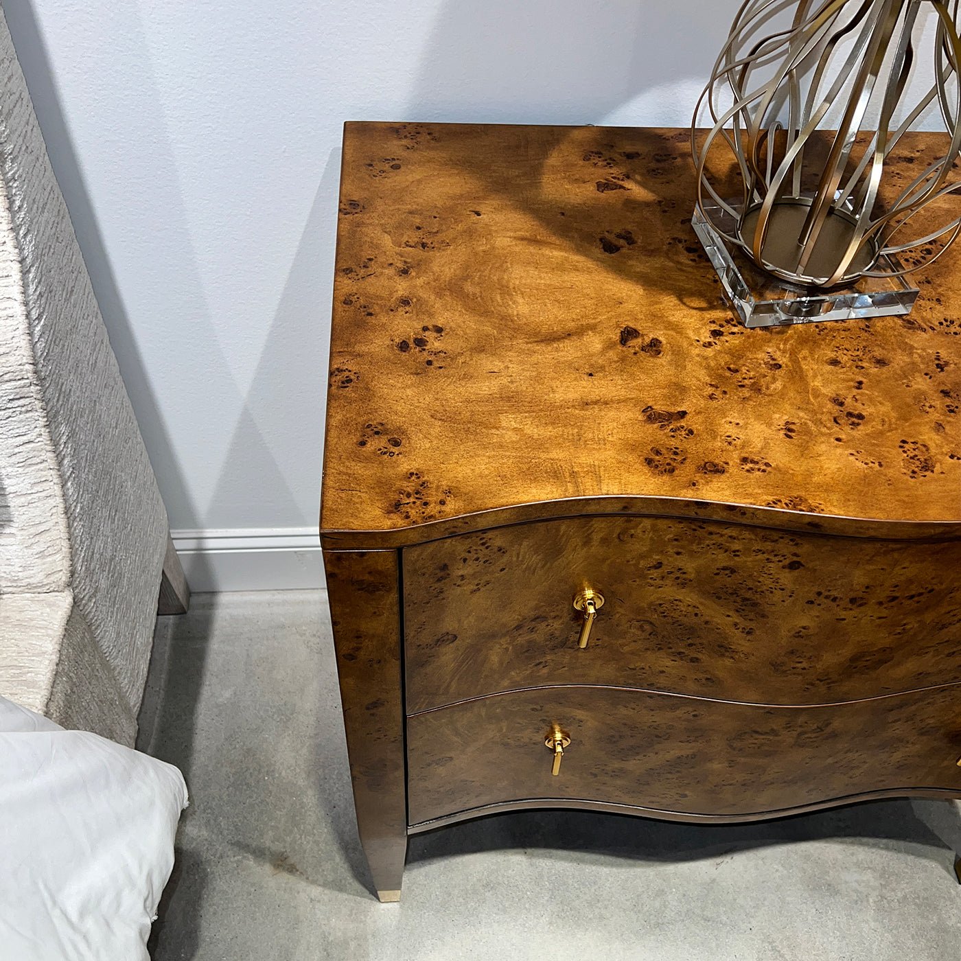 Top view of burl nightstand with lamp, in a bedroom.