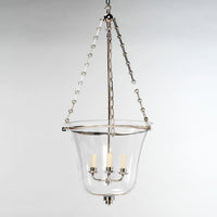 Hanging cloche lantern, nickel, against plain background.