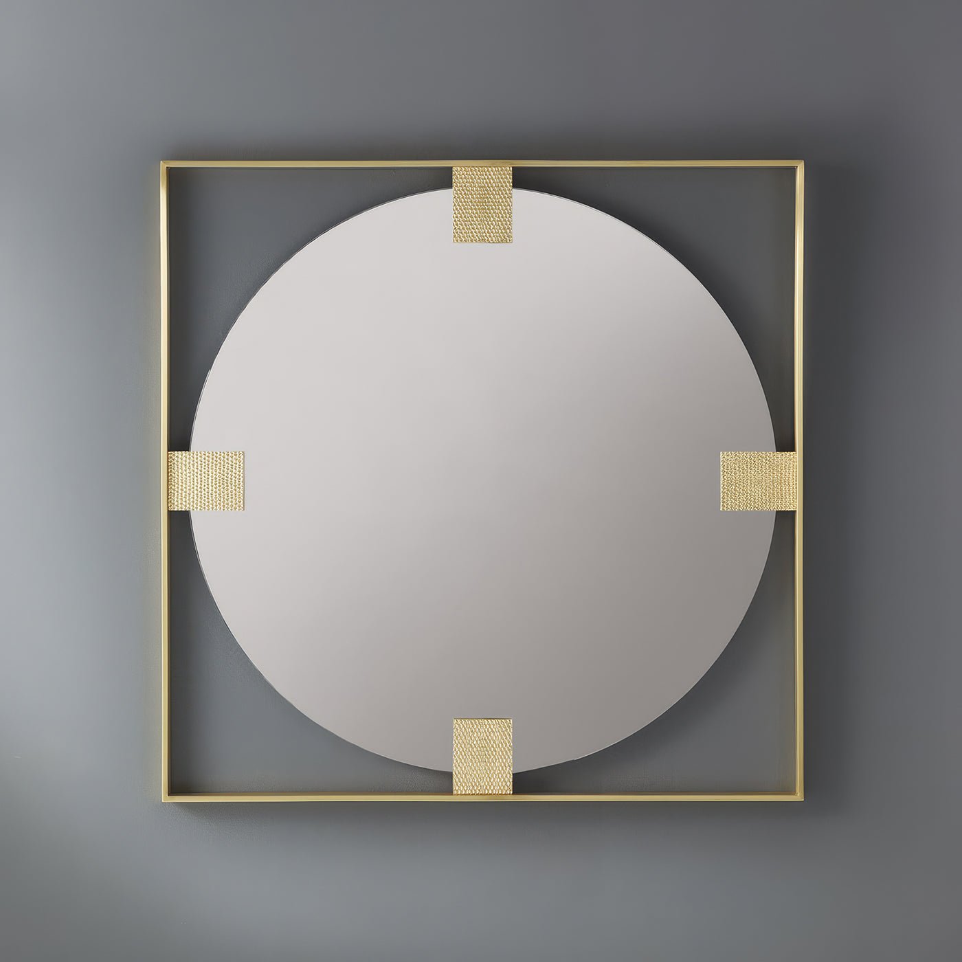 Brass mirror mounted on gray wall, reflective surface.
