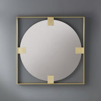 Brass mirror mounted on gray wall, reflective surface.