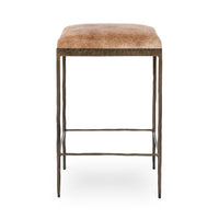 Straight-on view of tan backless hair-on-hide counter stool with slim iron legs and footrails.