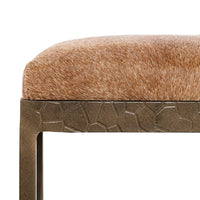 Close-up of the tan hair-on-hide seat edge and textured iron apron on the backless counter stool.