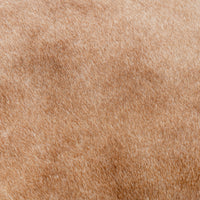 Tan hair-on-hide upholstery close-up showing the counter stool’s fine hair texture and natural mottling.