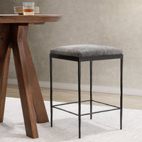 Gray backless hair-on-hide counter stool beside a wood counter table on a light rug.