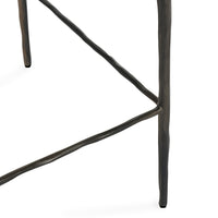 Detail of the hammered iron legs and footrail joints on the dark brown backless counter stool.
