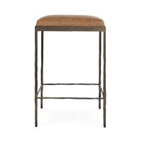 Straight-on view of tan backless leather counter stool with slim hammered iron legs.