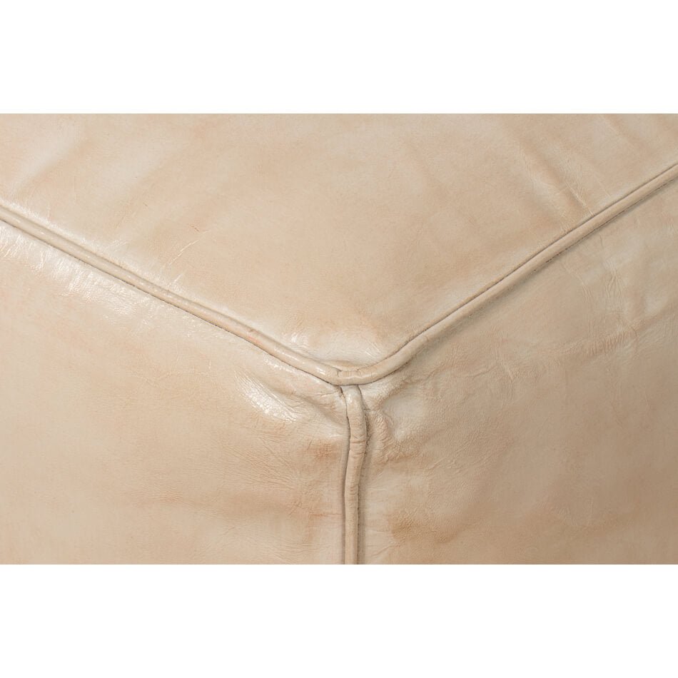 Beige leather cube stool, close-up corner detail.