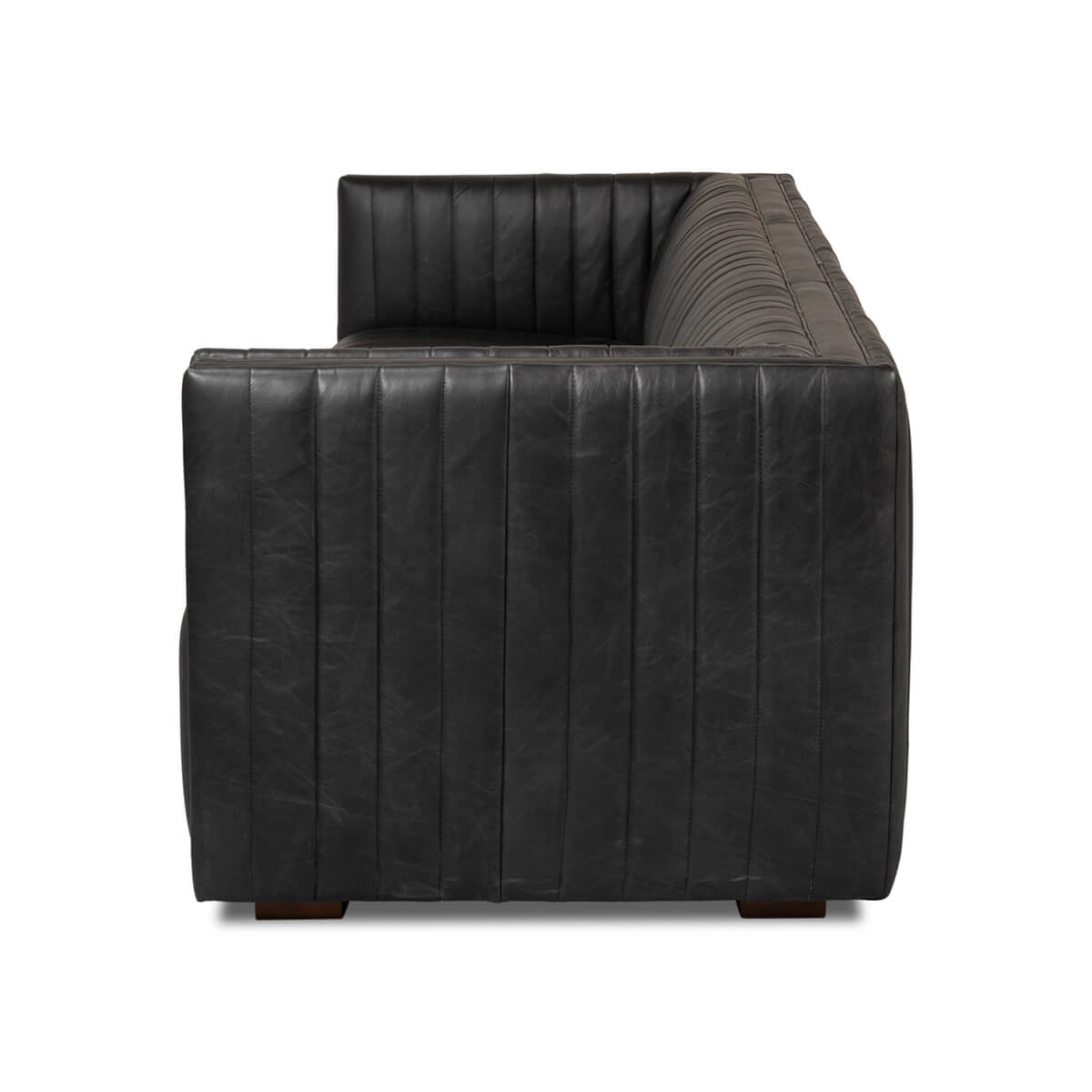 Black leather sofa armrest view, vertical stitching detail.