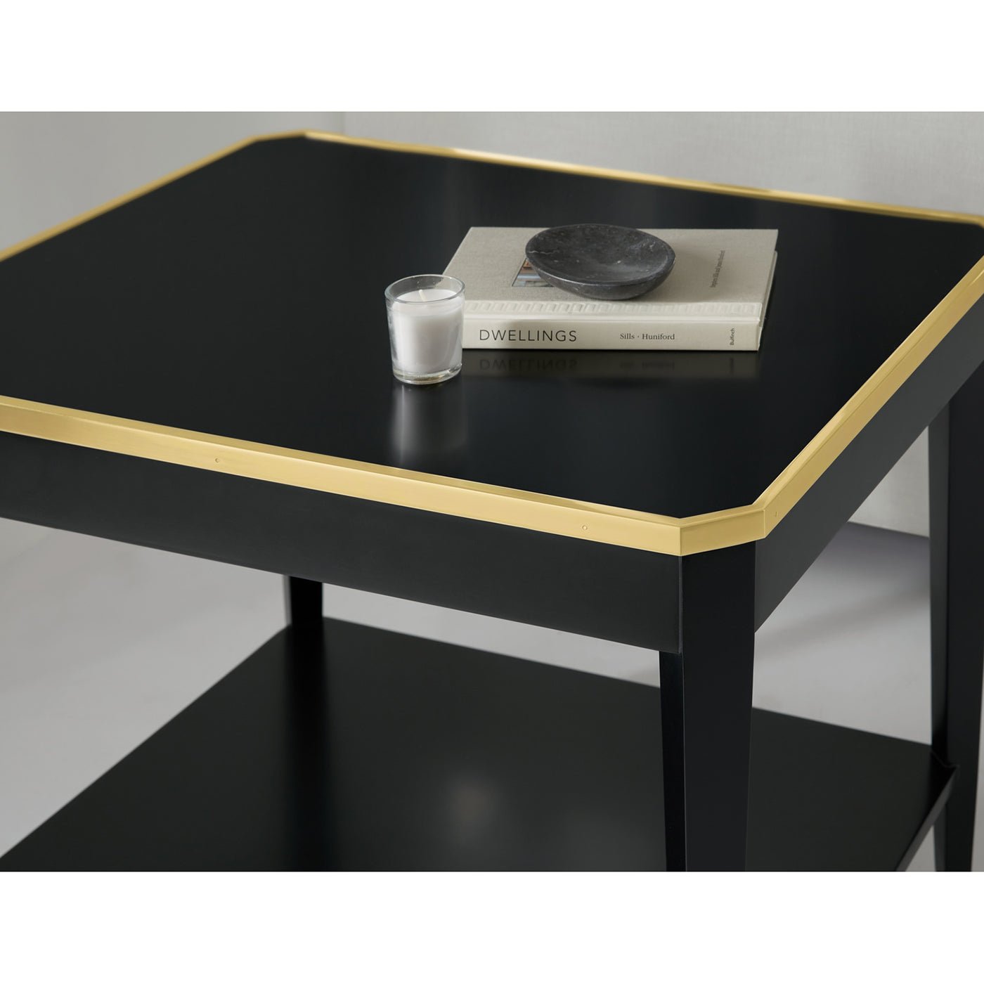 Top view of black end table with books and candle.