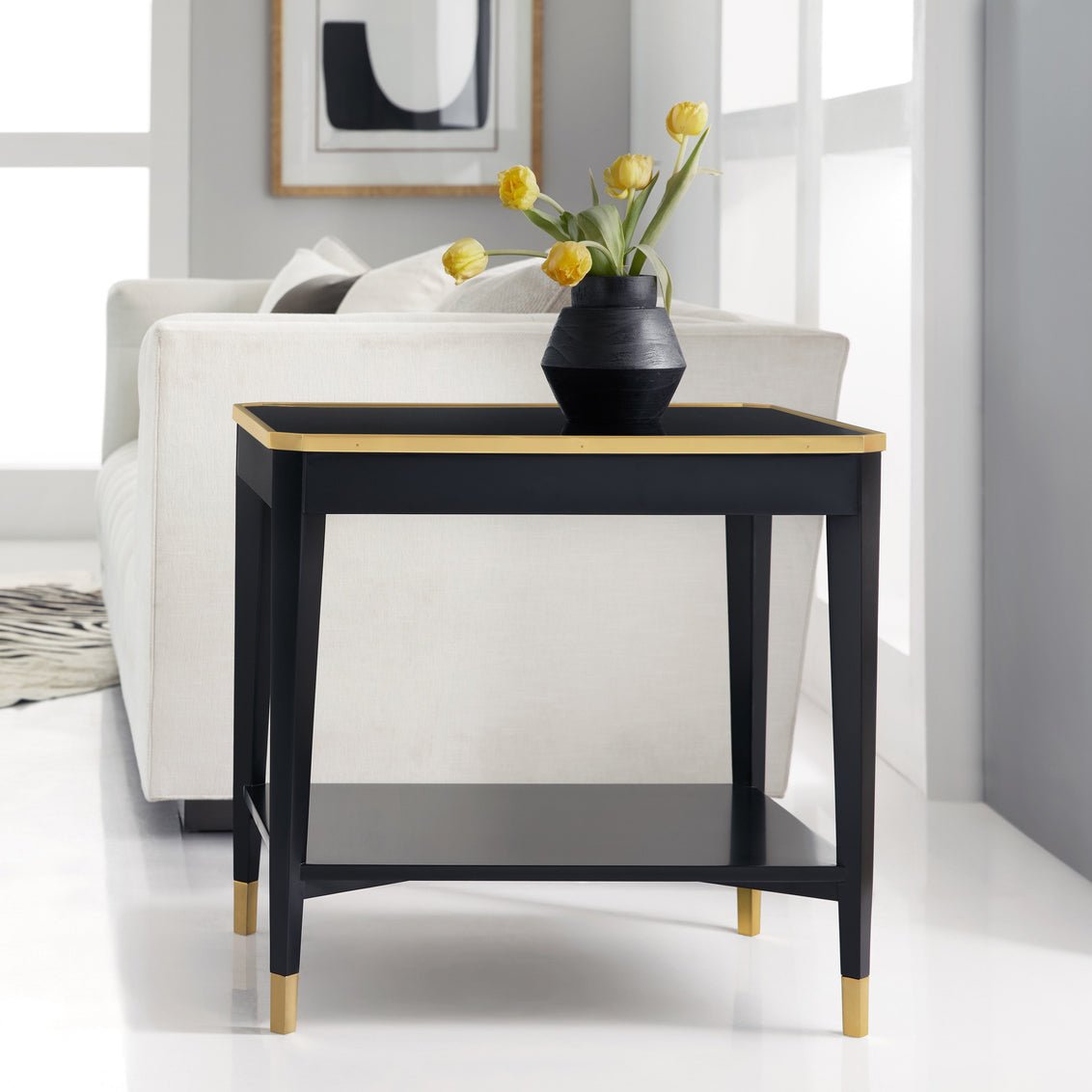 Black end table styled with vase next to sofa.