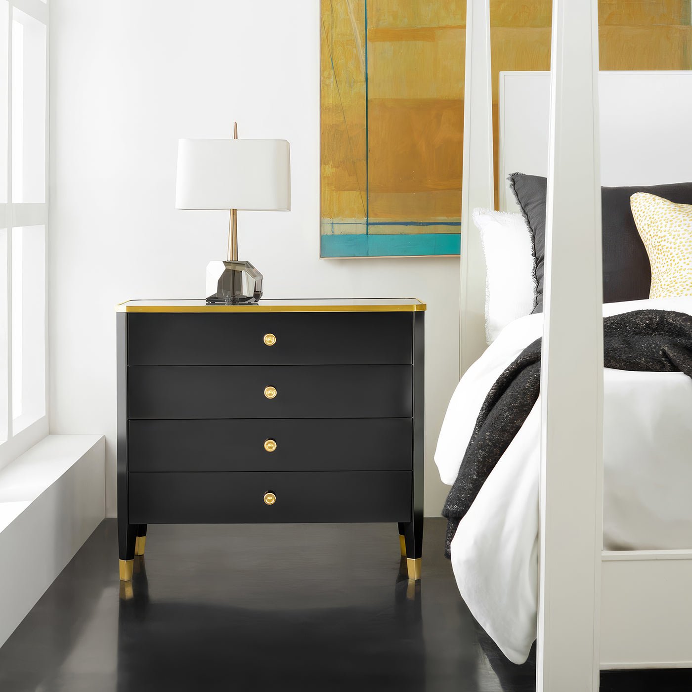 Black mid-century nightstand beside bed in modern bedroom.