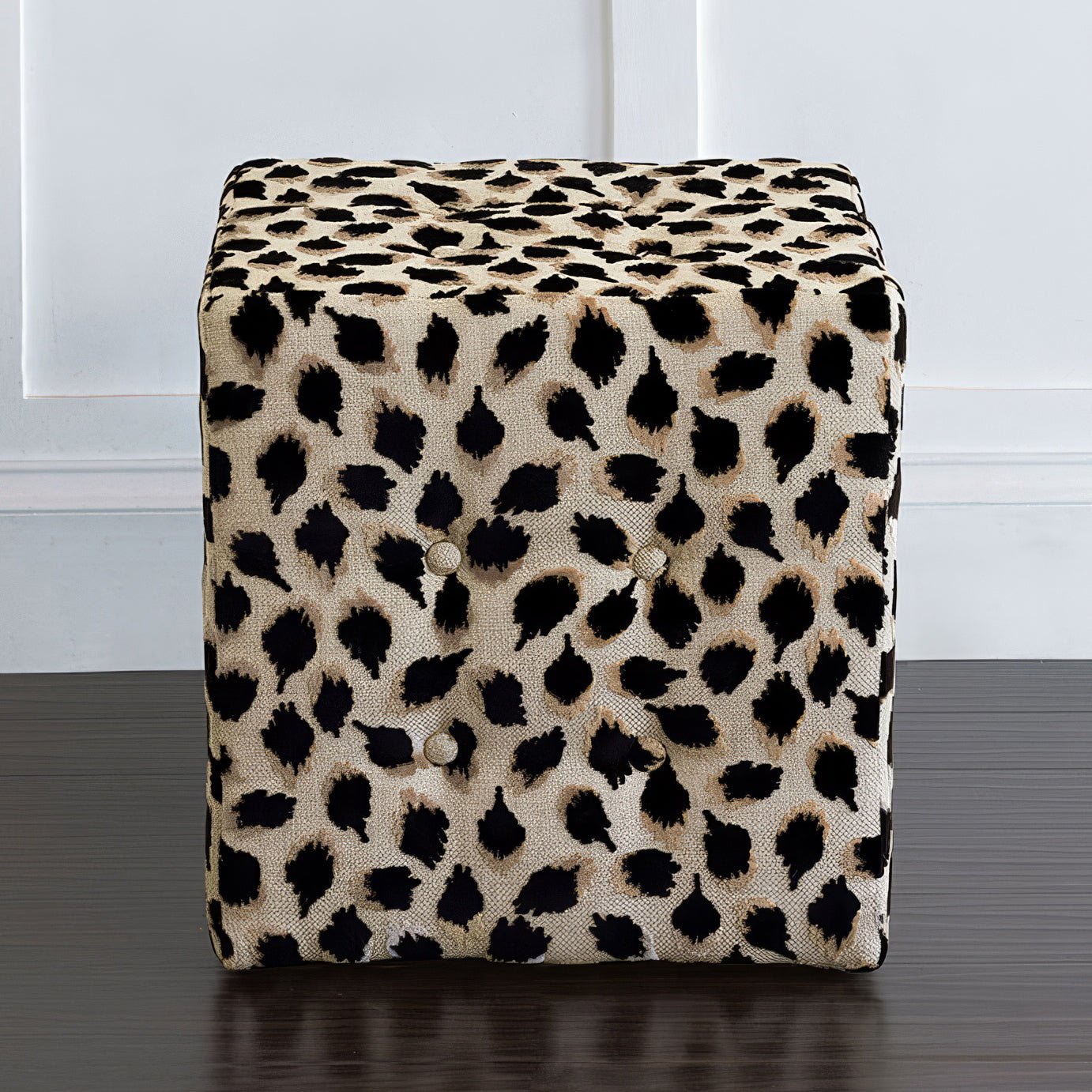 Black ocelot cube ottoman centered against white wall.