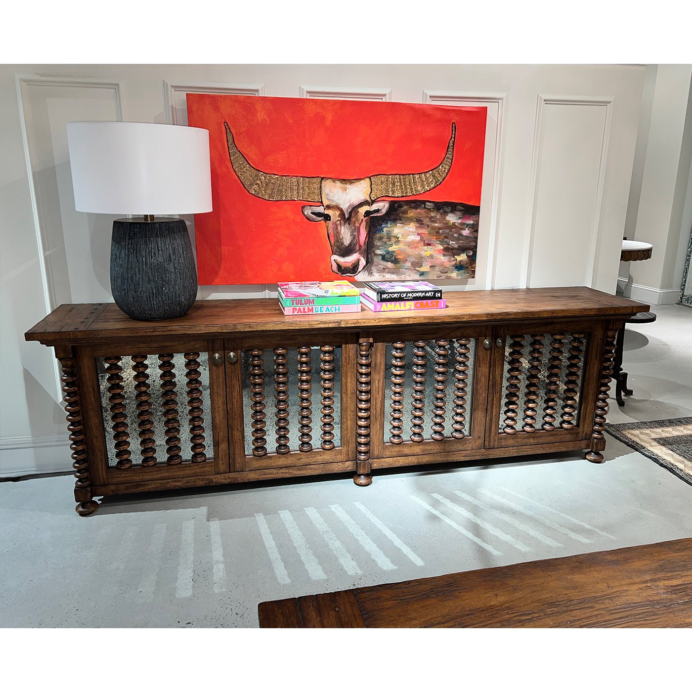 Console in room setting with lamp and art.