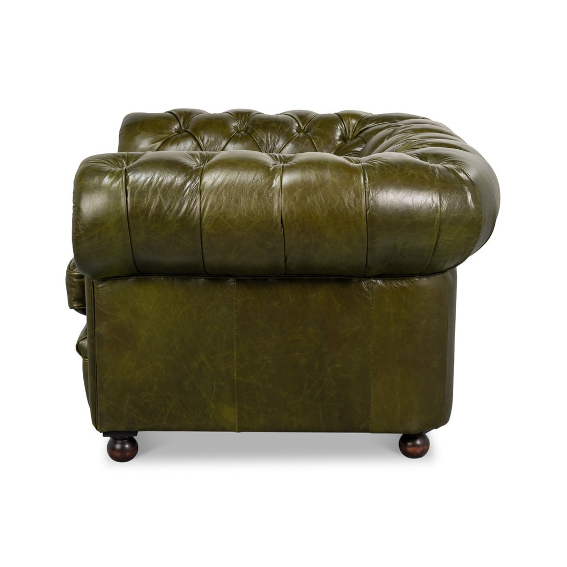 Green leather armchair, side view, tufted arm detail.