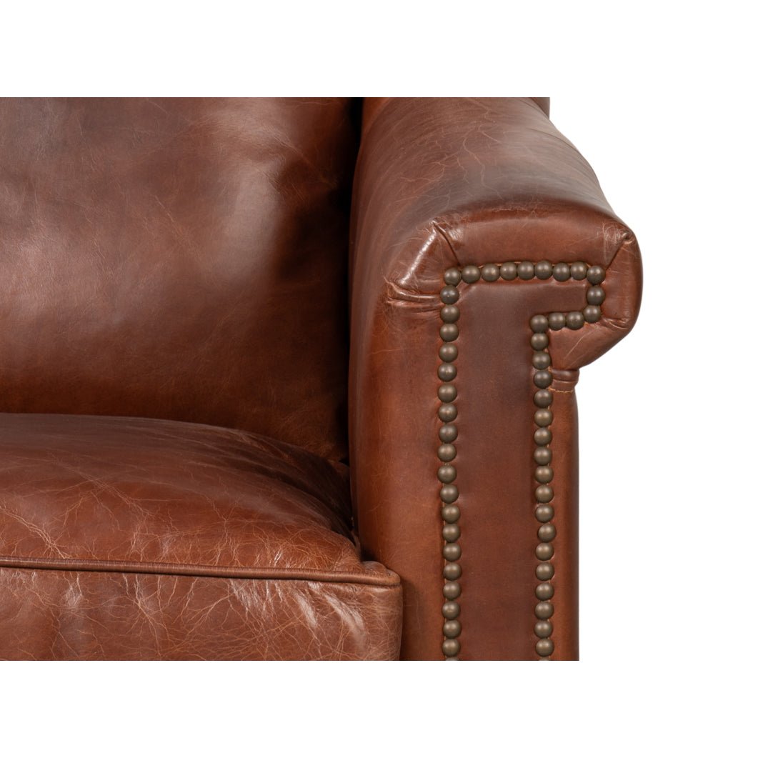 Close-up of armrest corner with nailhead trim on leather accent chair.