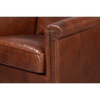 Close-up of armrest with nailhead trim on leather accent chair.