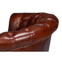 Top back detail of brown leather barrel chair.