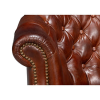 Arm detail of brown leather barrel chair.