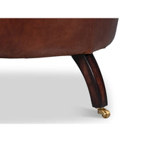 Rear leg of brown leather barrel chair with caster.