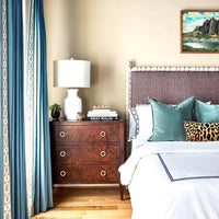 Burl walnut chest next to bed, styled interior.