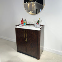 Burl wood bar cabinet styled with drinks and accessories.
