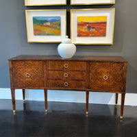 Burl wood sideboard against gray wall, art pieces above.