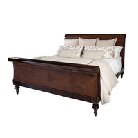 Sleigh bed with pillows and bedding, front view.