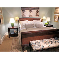 Sleigh bed in decorated room with lamps and bench.