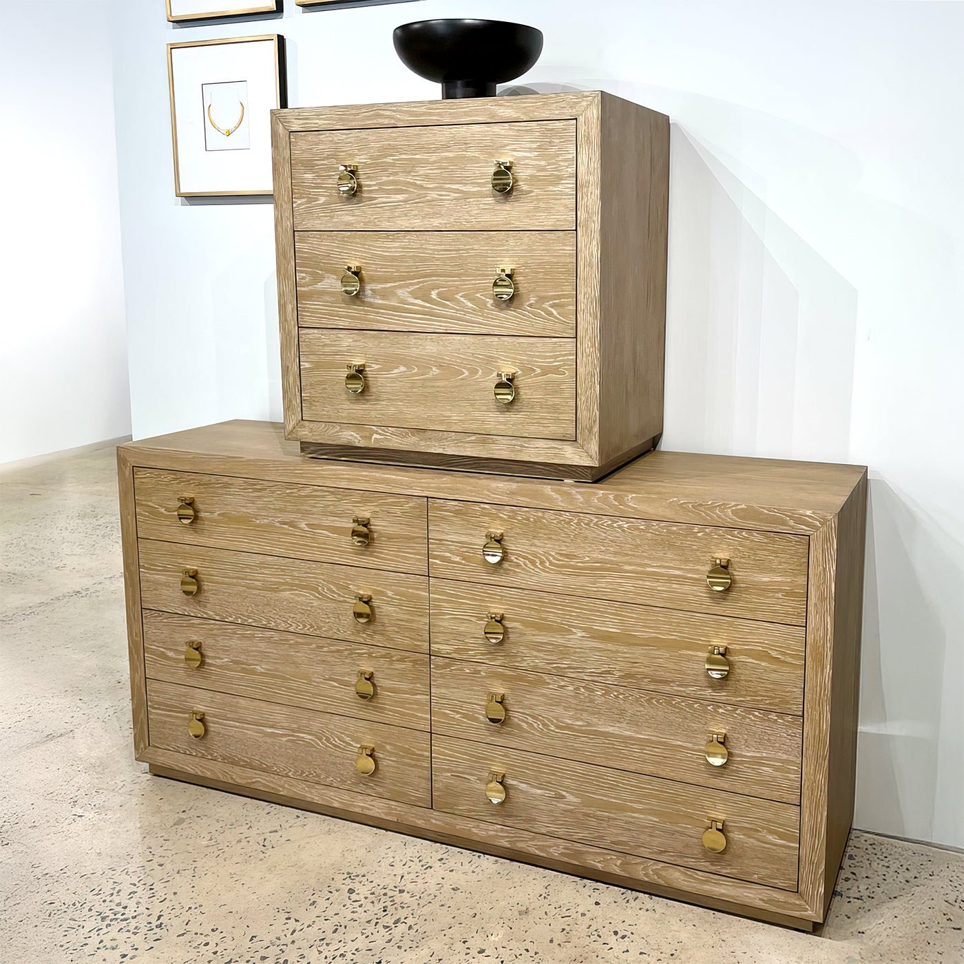 Cerused oak bedside chest atop matching dresser in showroom.