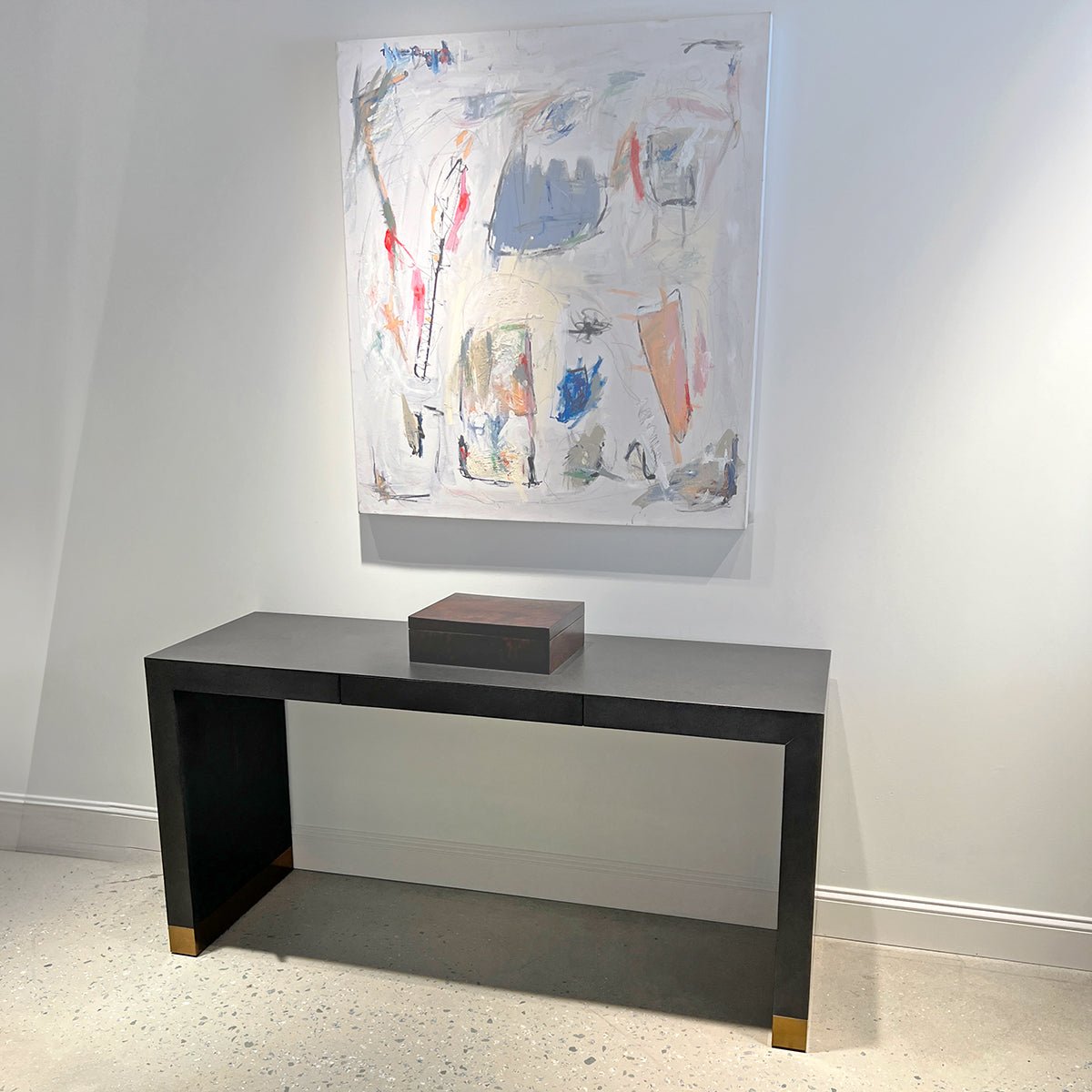Console table beneath abstract painting, modern interior setting.