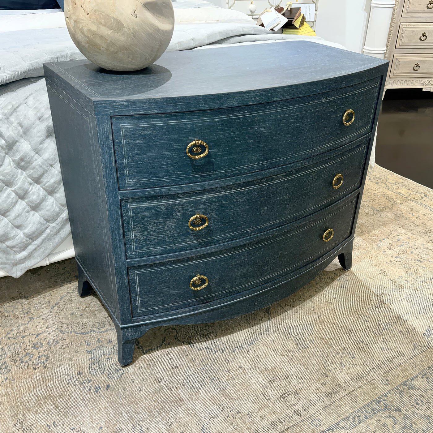 Blue chest in bedroom setting with textured area rug.