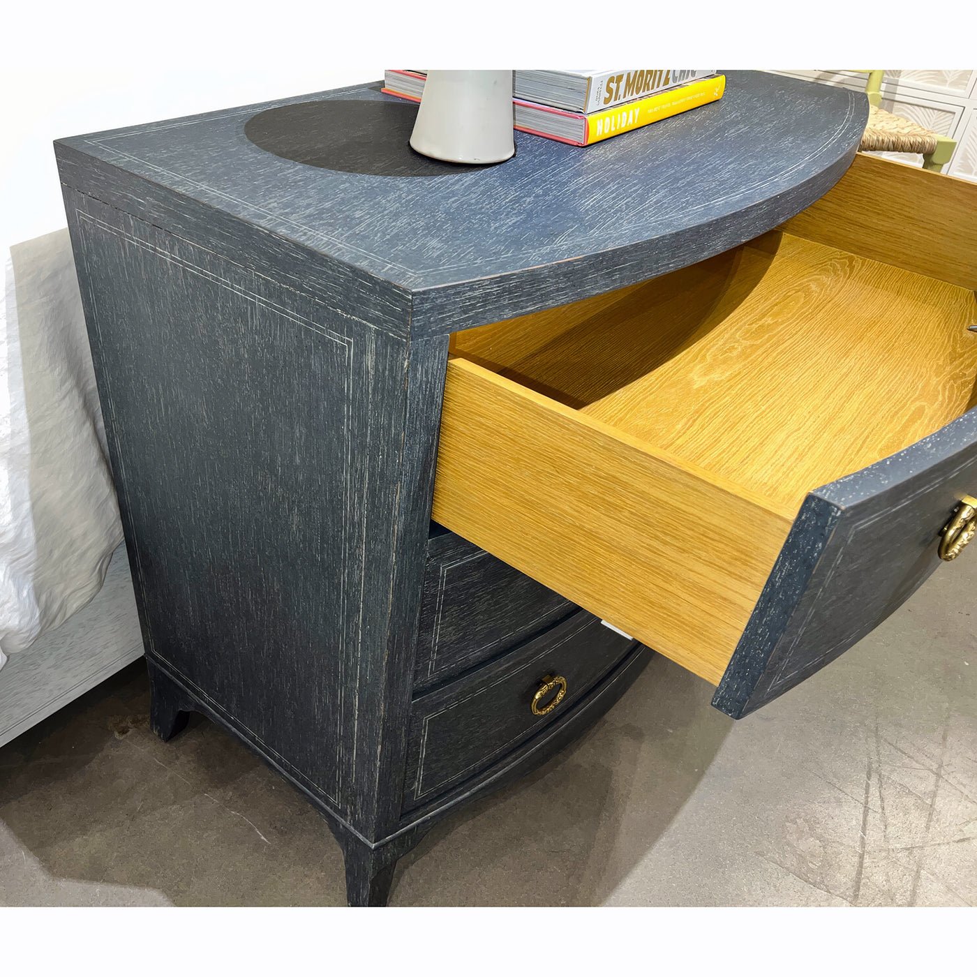 Open drawer of blue painted bedside chest with wood interior.