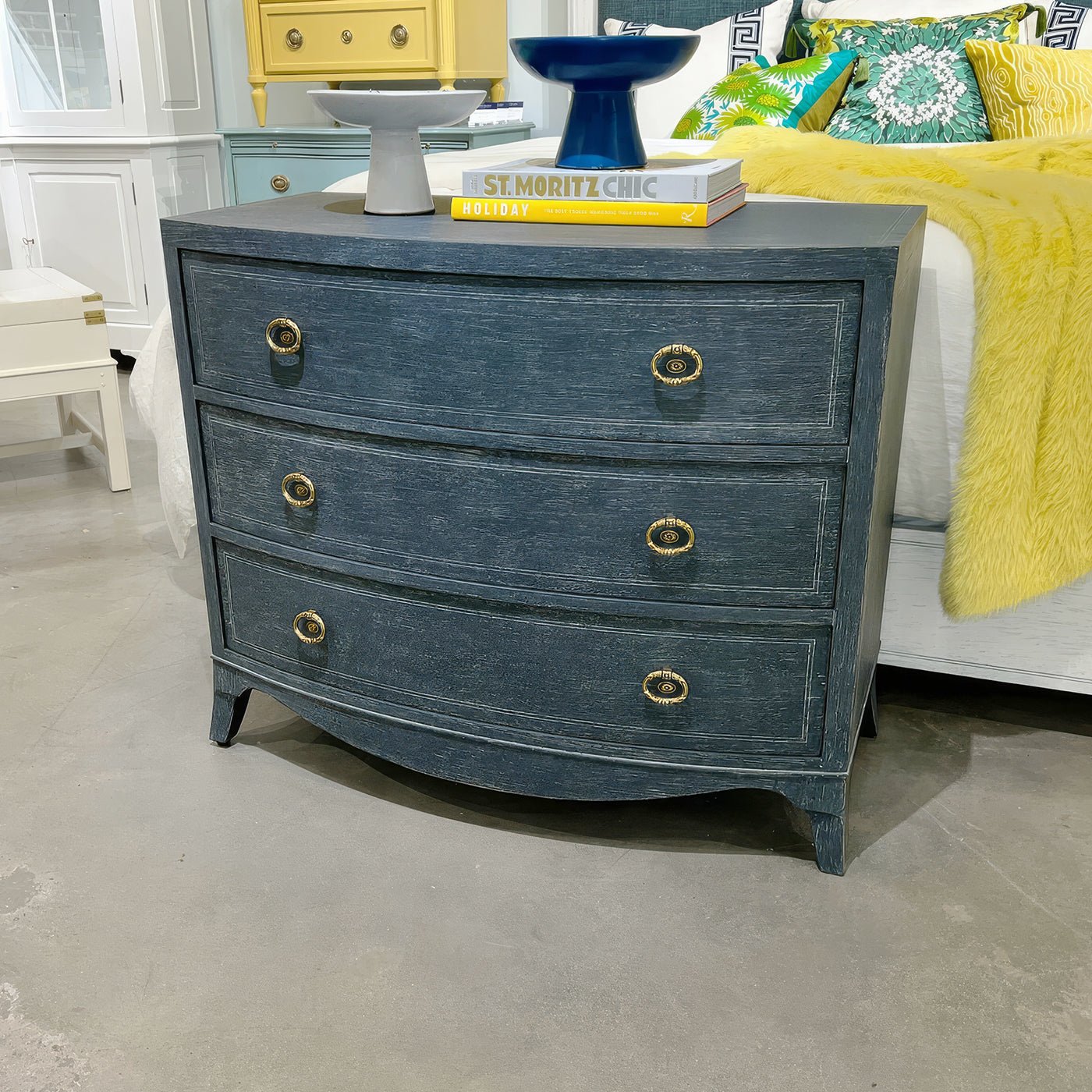 Blue bedside chest in showroom with decorative objects.