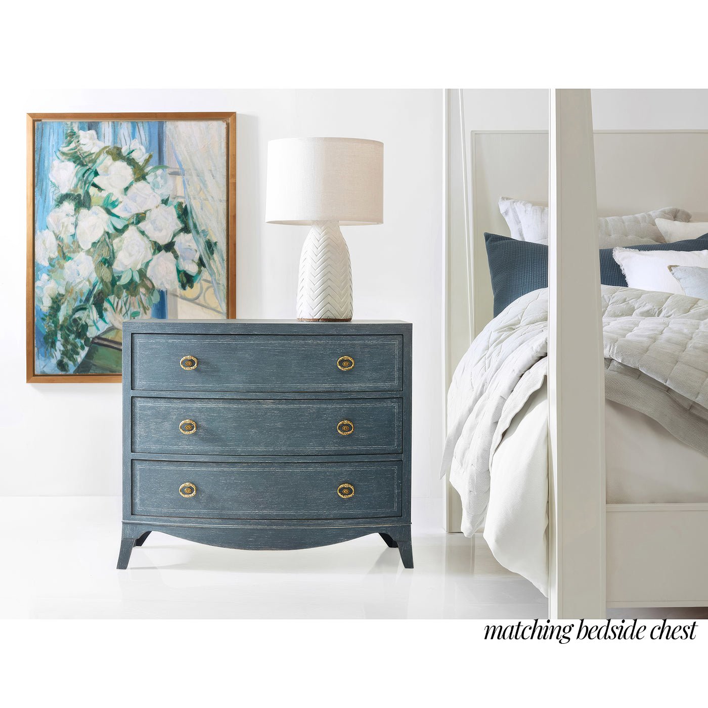 Matching bedside chest in bedroom with lamp and artwork.