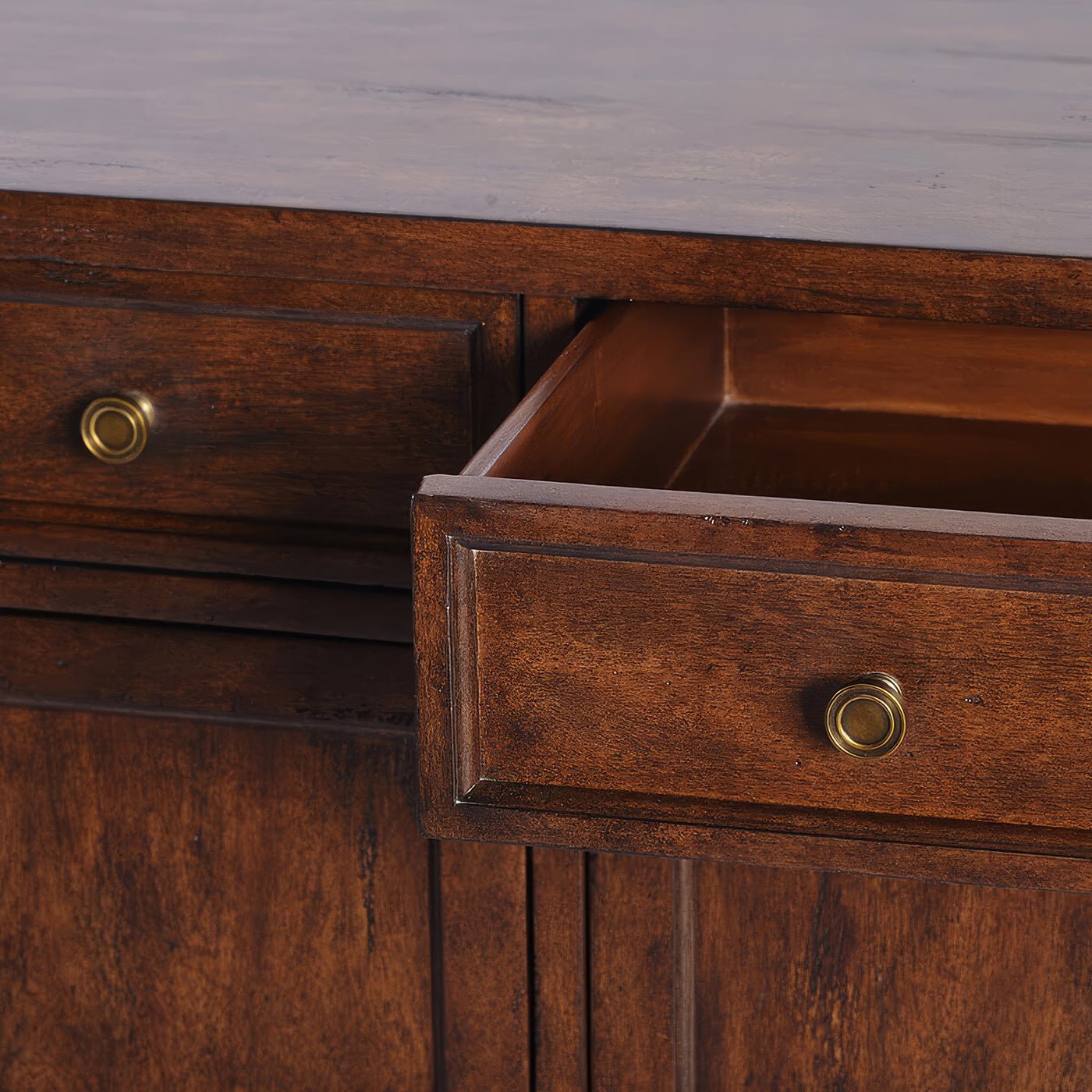 Close-up of open sideboard drawer with brass knob.