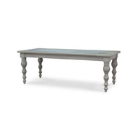 Angled view of grey farmhouse dining table, carved legs.