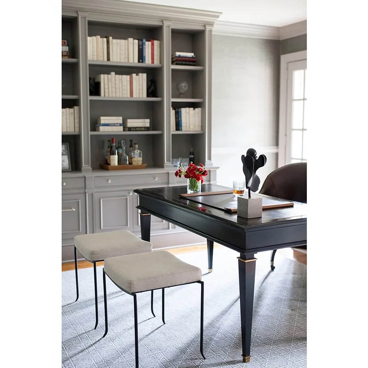 Black desk in styled living room with bookshelves.