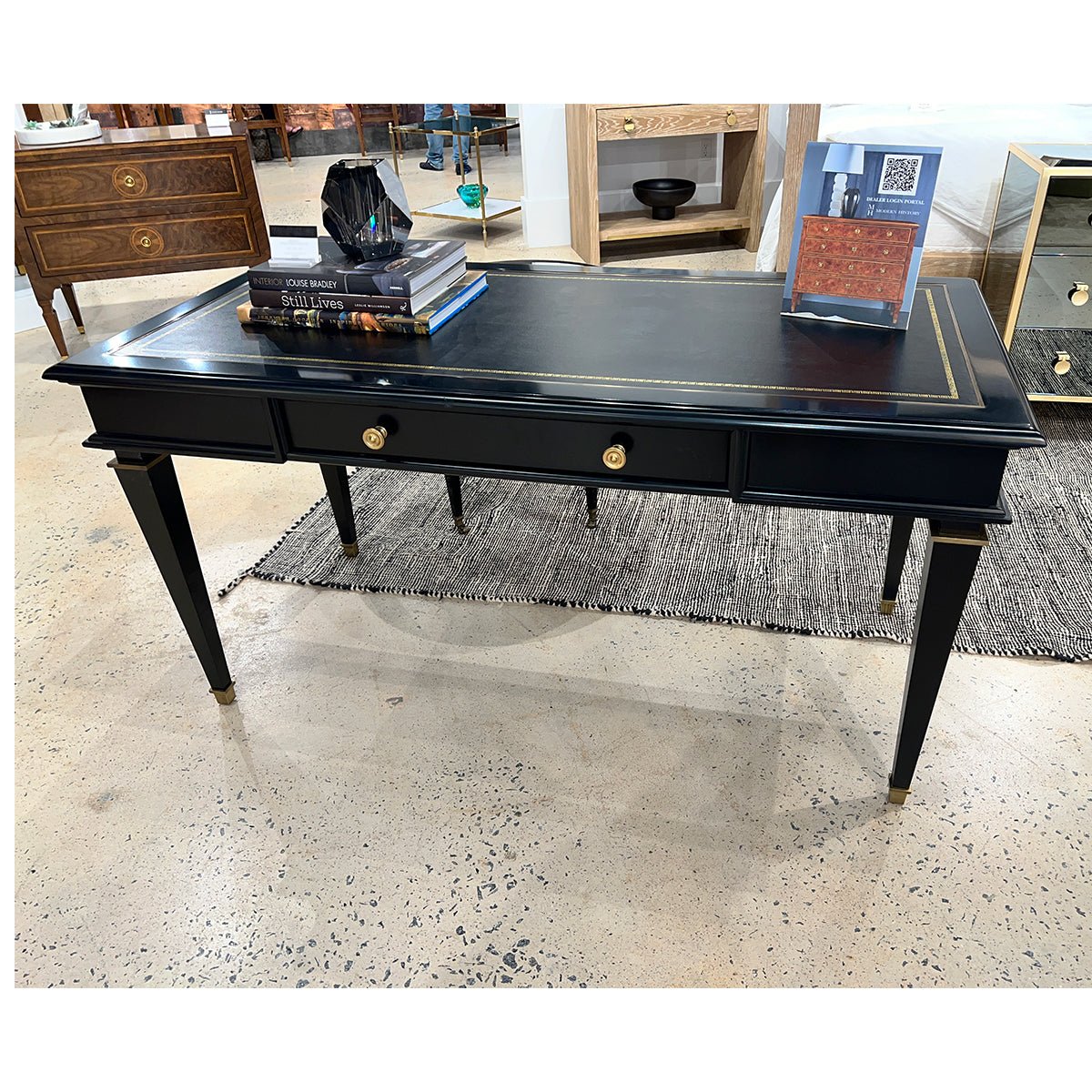 Black desk in showroom, decorated with books.
