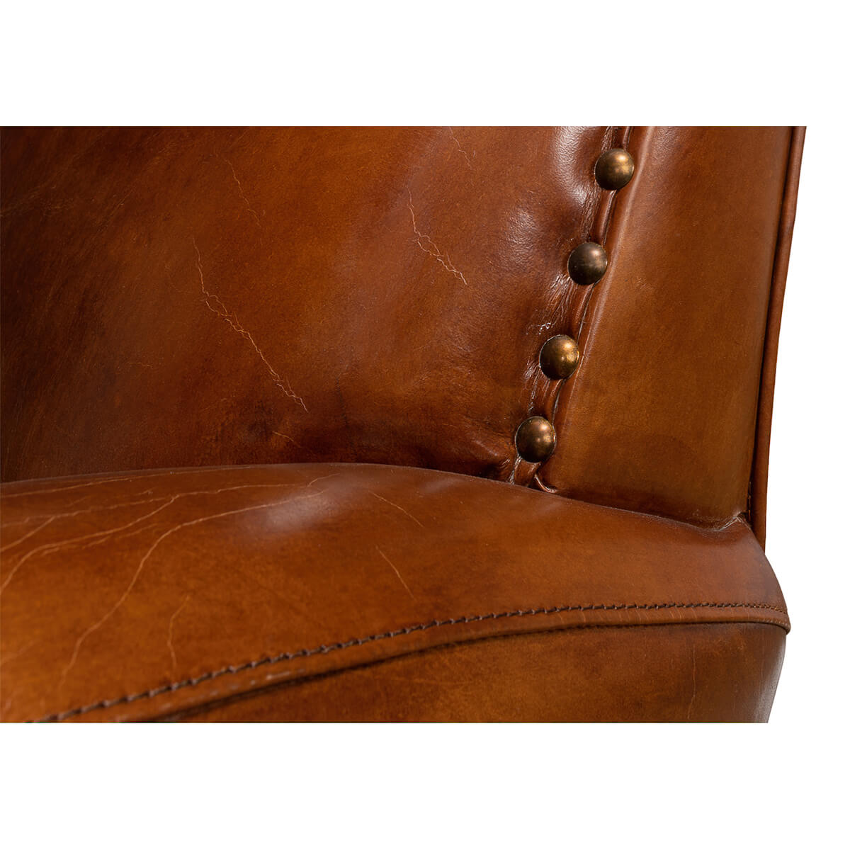 Detail of nailhead trim on brown leather armchair.