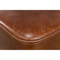 Close-up of textured leather ottoman corner detail.