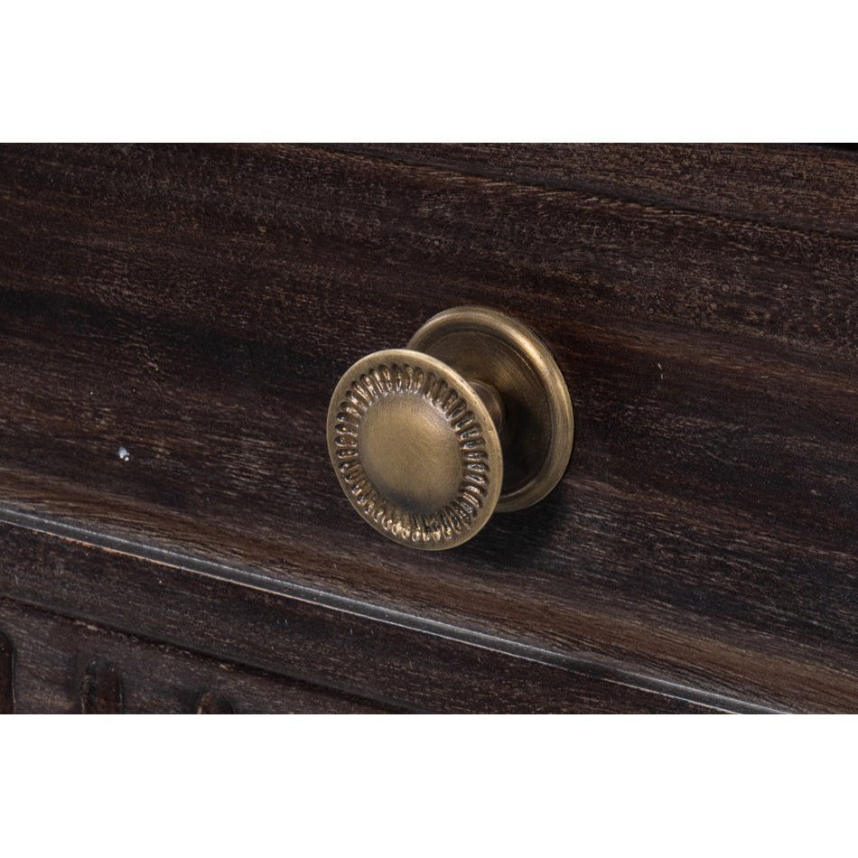 Close-up of metal drawer knob on console table.