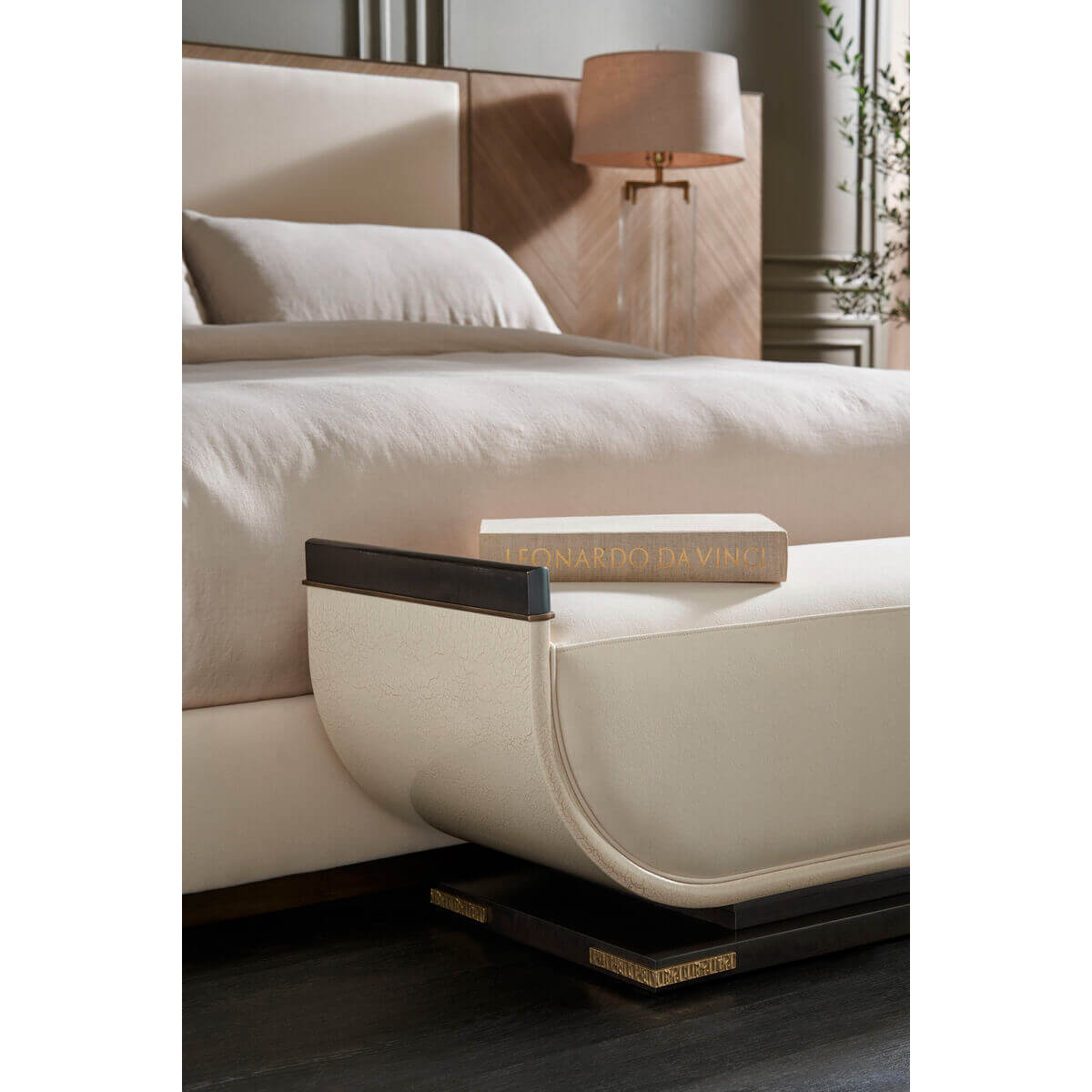 Close-up of bed footbench and decorative lamp beside bed.