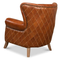 Side-back angle of quilted brown leather armchair.