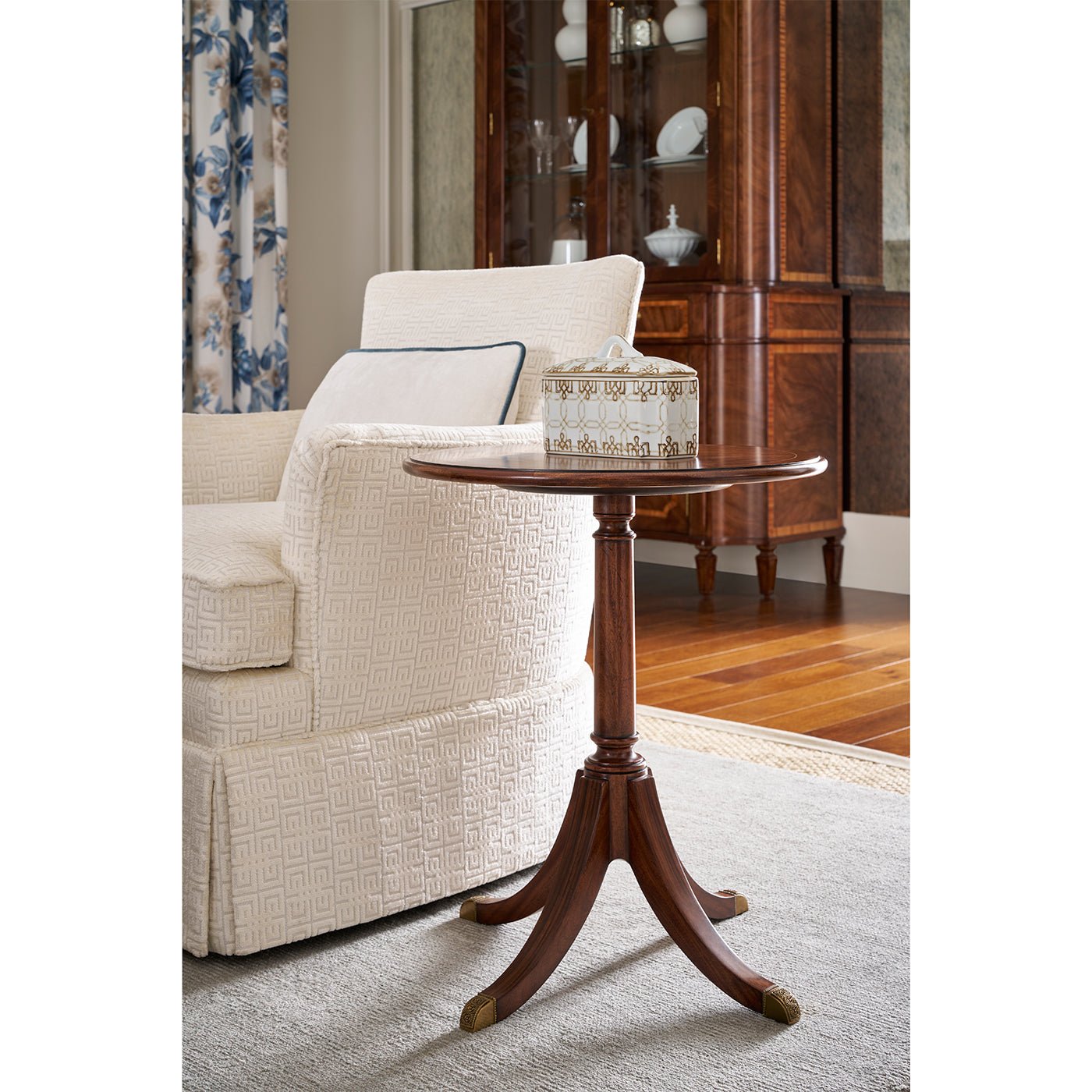 Classic round accent table beside cream sofa in living room.