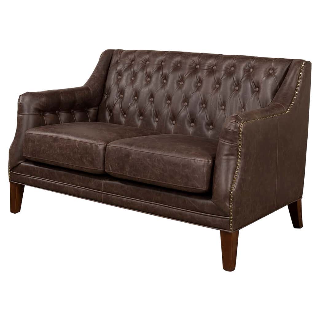 Angled view of classic tufted love seat, brown leather.