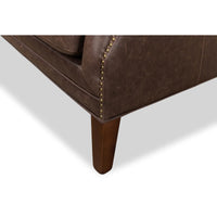 Wooden leg detail, brown tufted love seat corner.