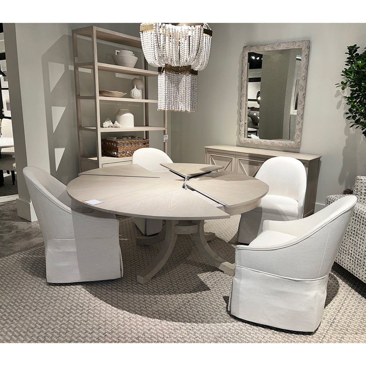 Round dining table with white skirted chairs in stylish room.